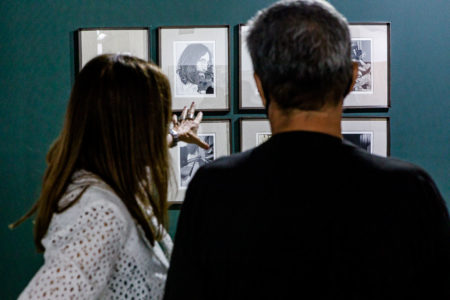 Casal observa parede com fotografias do John Lennon em um estande da última ArtRio.